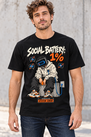 Male model wearing a black Social Battery 1% graphic T-shirt with low-battery screen-headed character and blue charging cable.